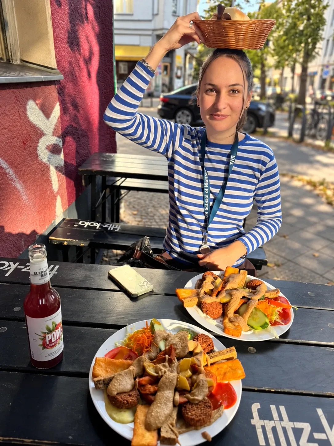 Person aus unserem Team balanciert einen Brotkorb auf dem Kopf, davor zwei volle Savannah-Teller auf dem Biertisch